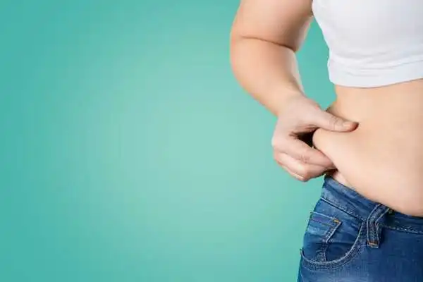 Image of woman pinching her love handles to show weight gain Dunmow